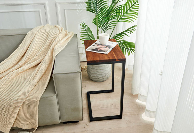 Modern Walnut C Table beside a gray sofa with a mug and magazine, styled with a potted palm