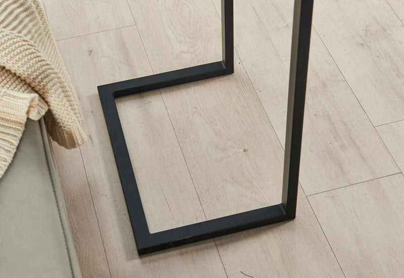 Detail of the Modern Walnut C Table black metal C-shaped base on light wood floor