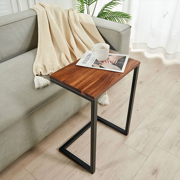 Modern Walnut C Table sliding under a sofa holding a coffee mug and magazine in a living room