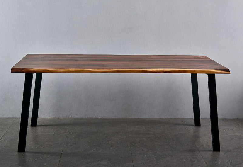 Front view of Live Edge Dining Table with walnut top and black angled metal legs against gray wall
