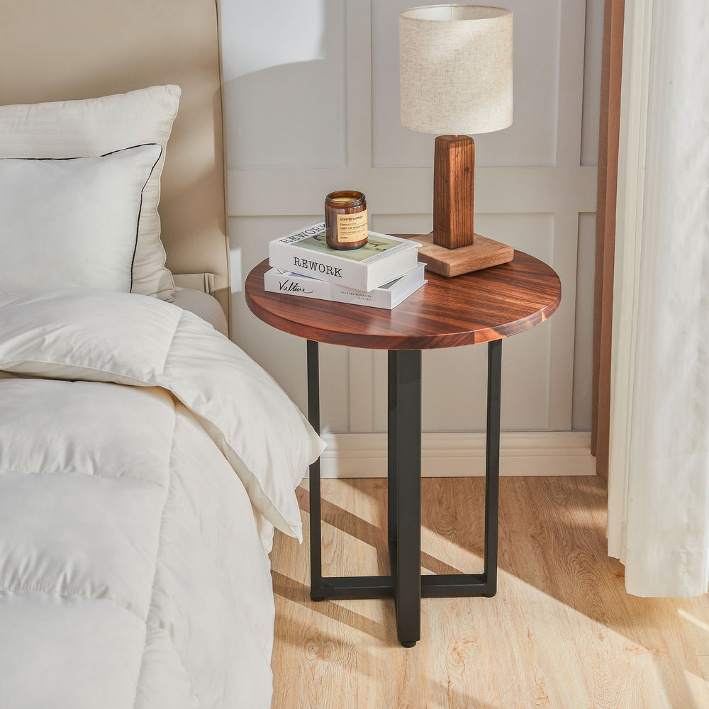 Round End Table in walnut used as a nightstand beside a bed with a lamp and books