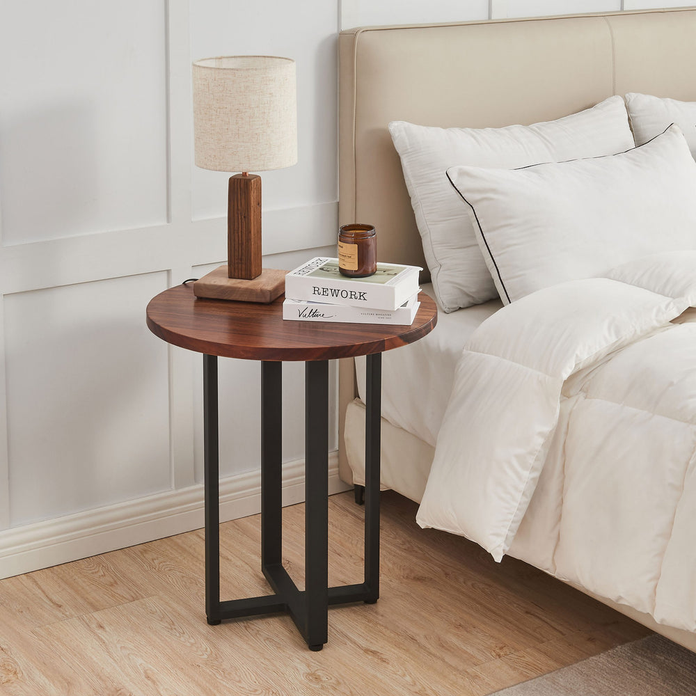 Round End Table in walnut with black base as a bedside table next to white bedding