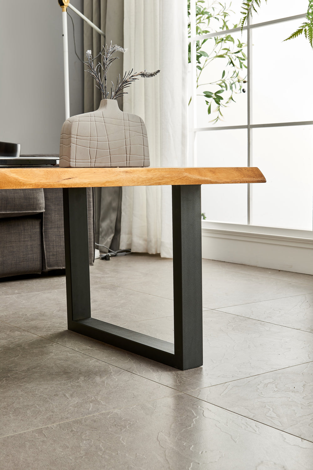 Close-up of Live Edge Coffee Table walnut top and black leg with a ceramic vase