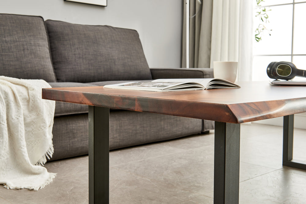 Close-up of Live Edge Coffee Table walnut edge in front of a gray sofa