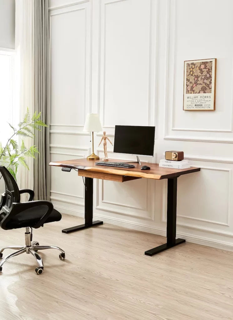 Adjustable Standing Desk in black with walnut top and drawer beside an office chair