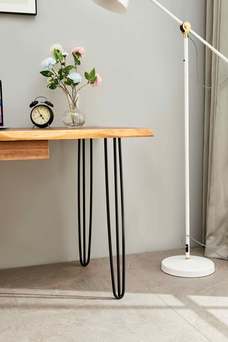 Close-up of Live Edge Desk black hairpin legs and walnut top by a floor lamp