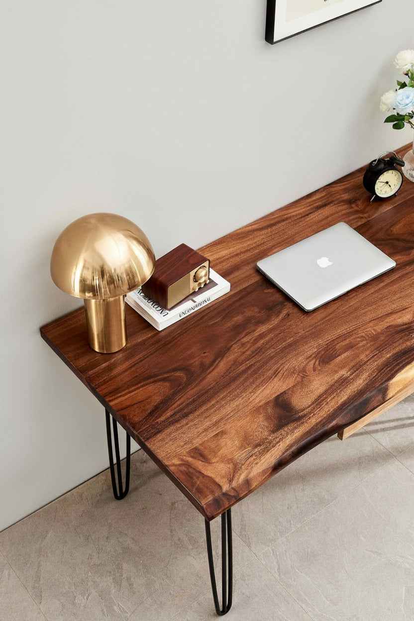 Wooden desk with hairpin legs, gold lamp, and laptop on a light gray wall background