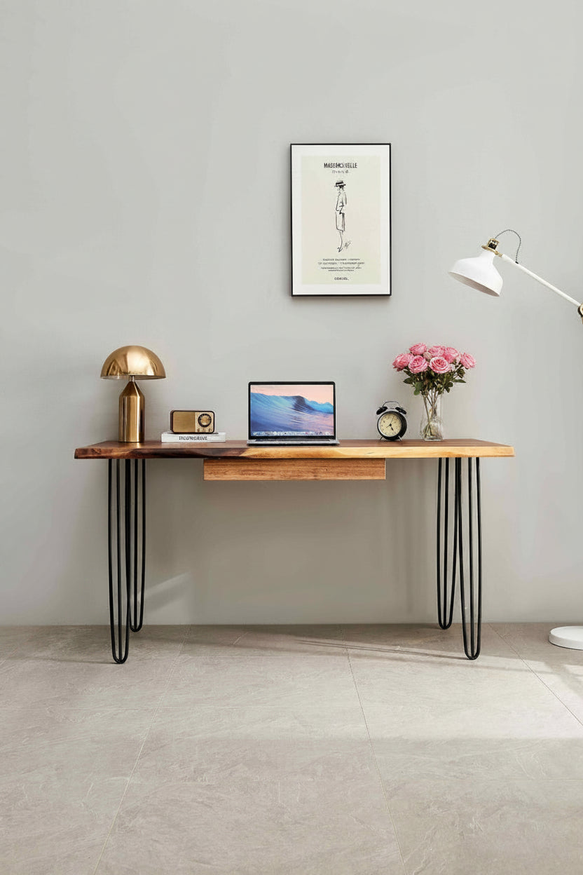 Wooden desk with laptop, lamp, and decor items against a gray wall.