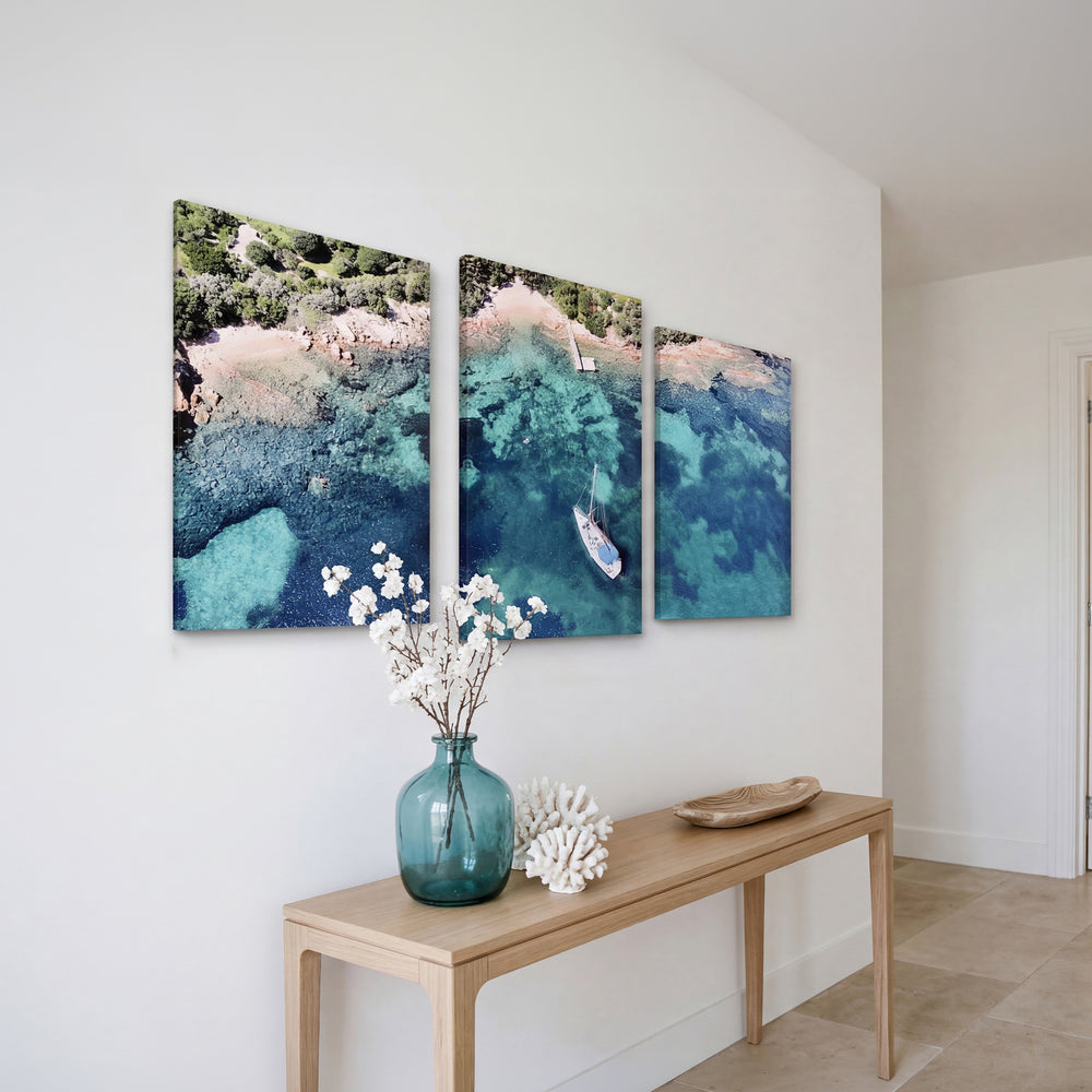 3-Panel Ocean canvas art hung at an angle above a console table with white flowers