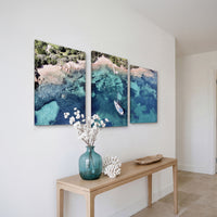 3-Panel Ocean canvas art hung at an angle above a console table with white flowers