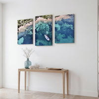 3-Panel Ocean canvas art angled on a wall above a console with flowers and coral