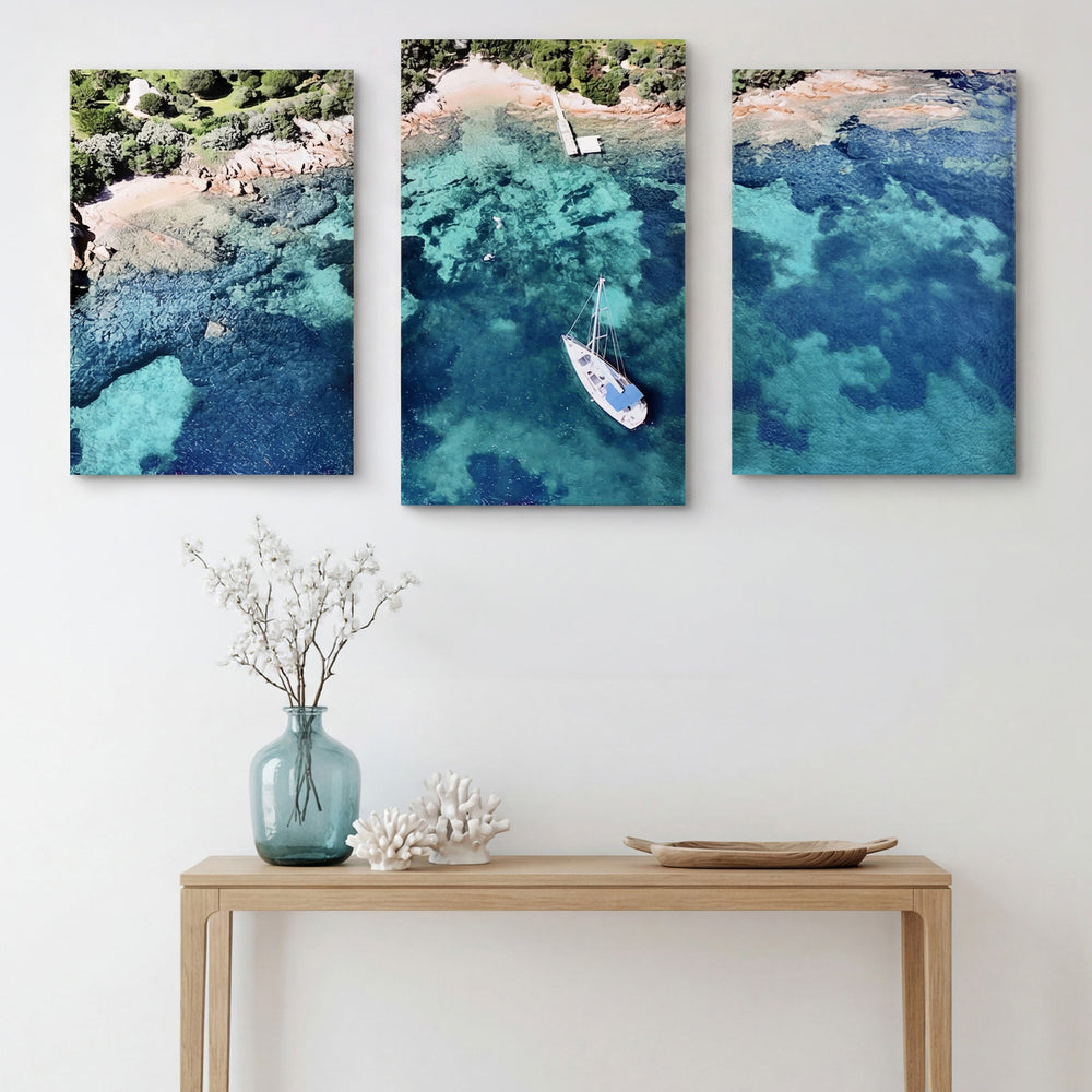 3-Panel Ocean canvas wall art hung above a light wood console with a vase and coral