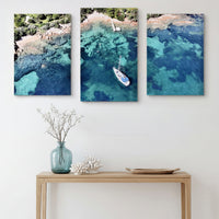 3-Panel Ocean canvas wall art hung above a light wood console with a vase and coral