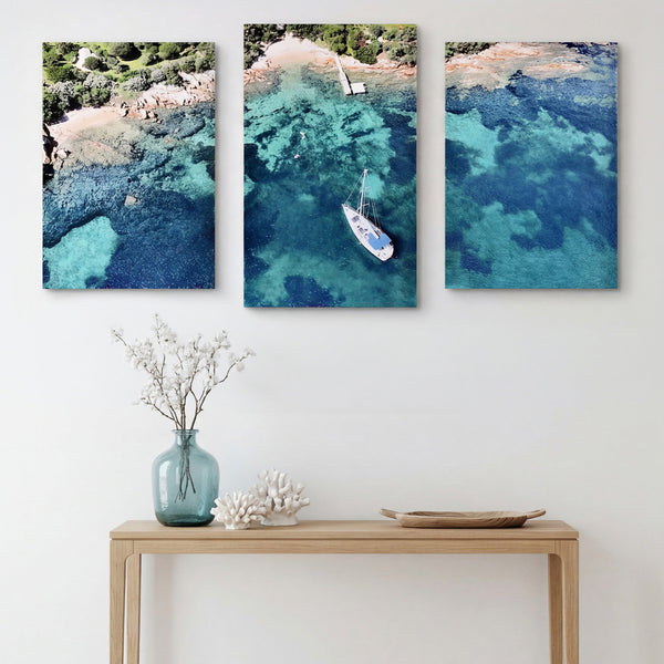3-Panel Ocean canvas wall art hung above a light wood console with a vase and coral
