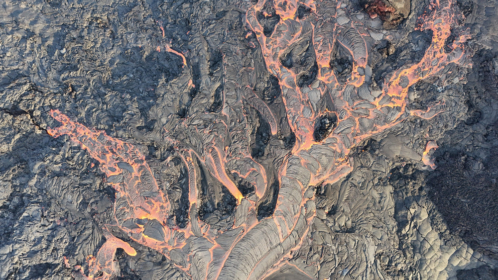 Aerial drone photo of branching orange lava flows cutting through gray volcanic rock