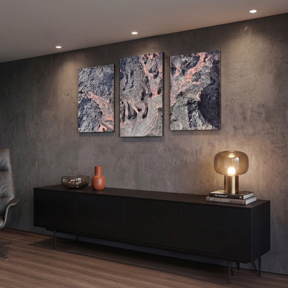3-Panel Lava canvas wall art above a long black credenza with a glass lamp and books